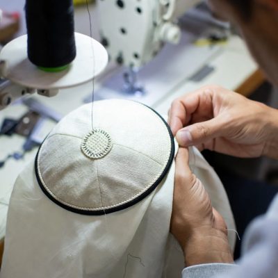 Elegant white satin Kippah with intricate gold rim embroidery patterns.